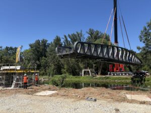 Grue levant une passerelle métallique au-dessus d'une rivière sur le chantier Génie Batignolles.
