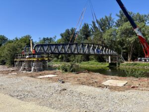 Installation d'une passerelle métallique par grue Dartus au-dessus d'une rivière sur un chantier.
