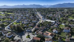 Vue aérienne d'un quartier résidentiel avec rond-point central et chaîne des Pyrénées à l'horizon.